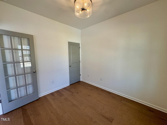 spare room with dark wood-type flooring and baseboards