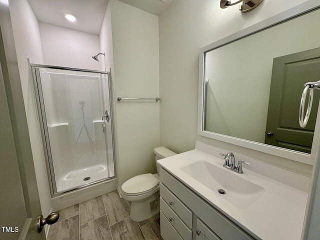 full bath with toilet, a stall shower, wood finished floors, and vanity