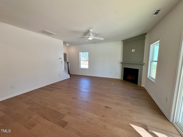 unfurnished living room featuring a large fireplace, visible vents, baseboards, ceiling fan, and light wood-style floors