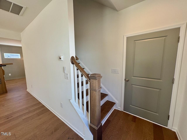 staircase featuring wood finished floors, visible vents, and baseboards