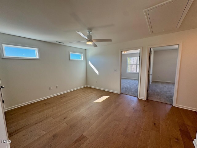 unfurnished room featuring plenty of natural light, wood finished floors, visible vents, and attic access