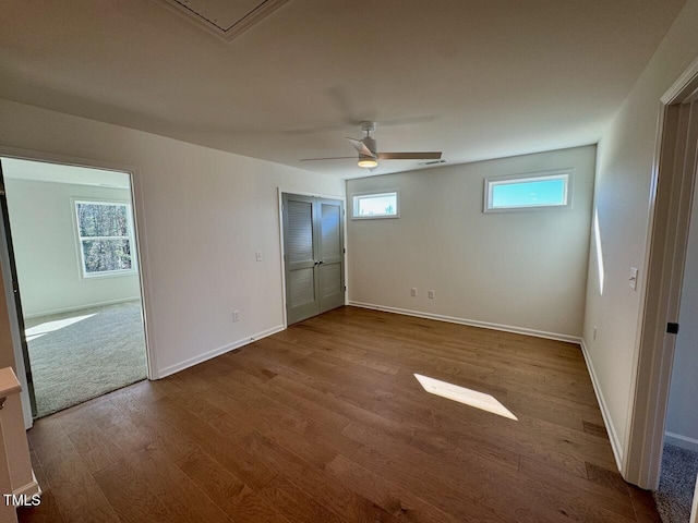 unfurnished bedroom featuring visible vents, multiple windows, baseboards, and wood finished floors