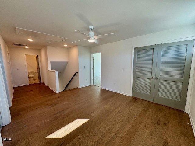 empty room with visible vents, attic access, ceiling fan, wood finished floors, and baseboards