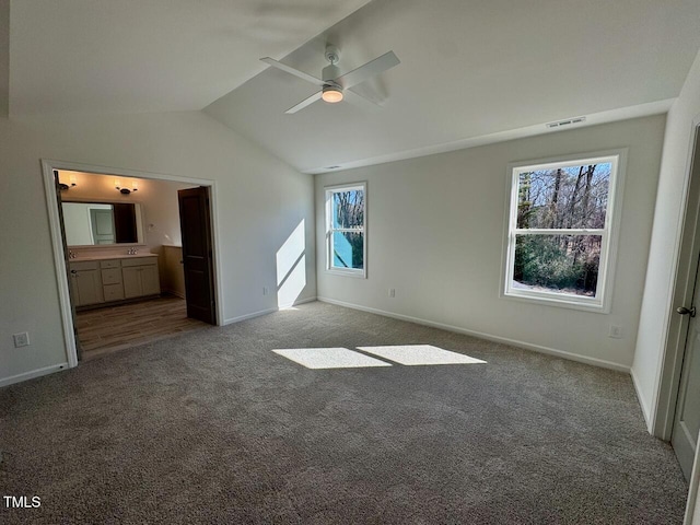 unfurnished bedroom with visible vents, baseboards, vaulted ceiling, carpet, and ensuite bath