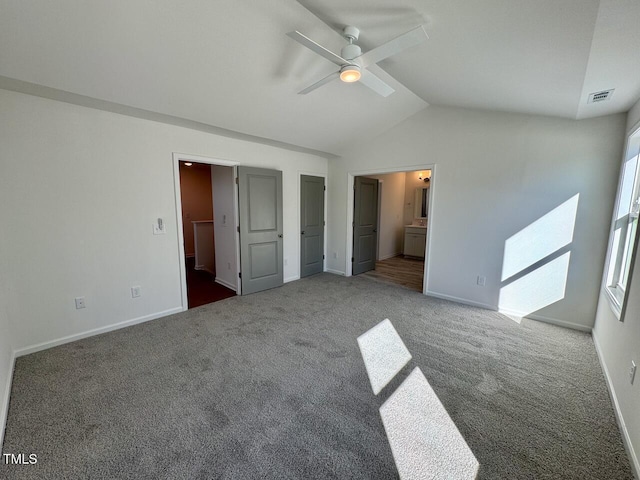 unfurnished bedroom with baseboards, visible vents, connected bathroom, vaulted ceiling, and carpet flooring