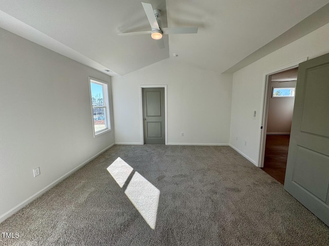 unfurnished bedroom featuring carpet floors, multiple windows, baseboards, and vaulted ceiling