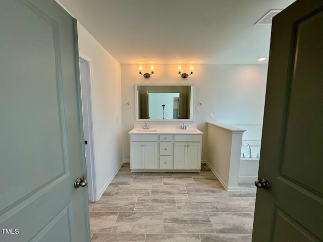 bathroom with a sink, double vanity, a garden tub, and visible vents