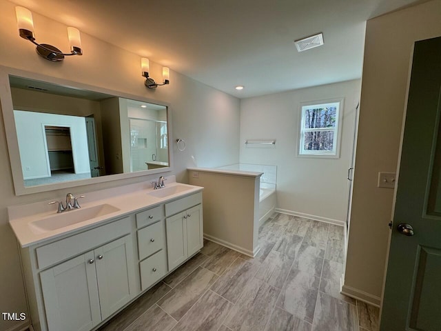 full bathroom featuring double vanity, a stall shower, visible vents, and a sink