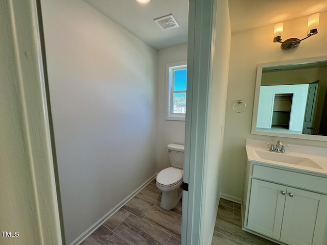 bathroom featuring baseboards, visible vents, vanity, and toilet