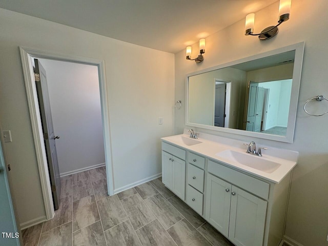 bathroom with a sink, baseboards, and double vanity