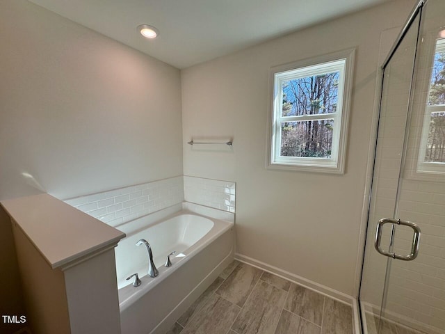 bathroom with recessed lighting, a shower stall, a bath, and baseboards