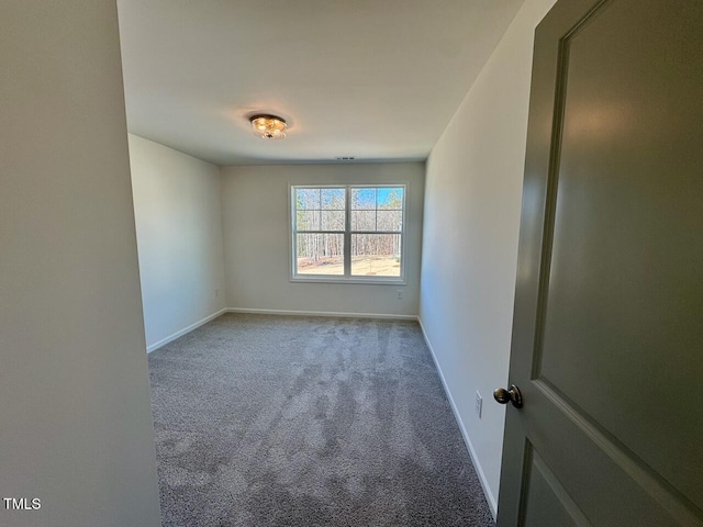 carpeted spare room featuring baseboards