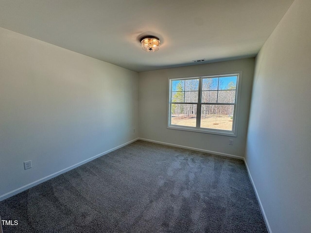 spare room featuring carpet floors, visible vents, and baseboards