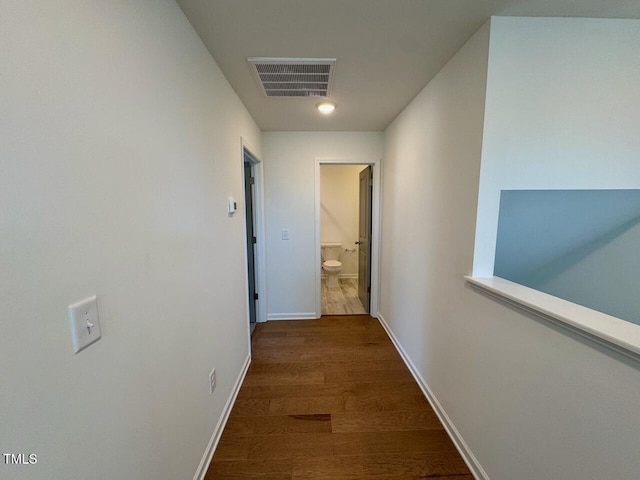 hall featuring baseboards, visible vents, and wood finished floors