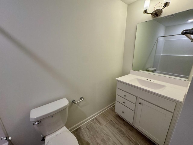 bathroom featuring toilet, vanity, baseboards, and wood finish floors