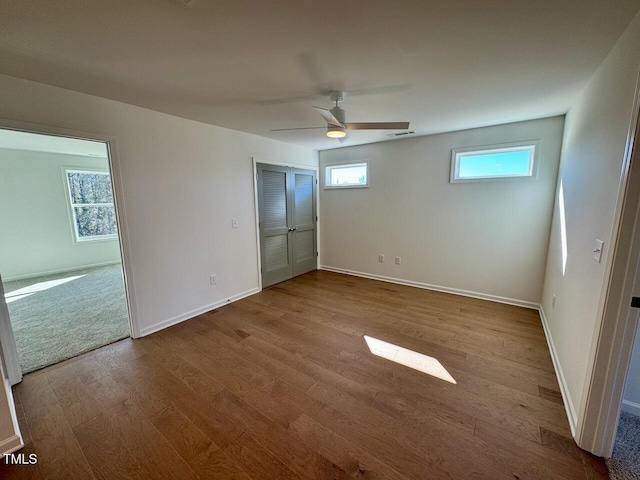 unfurnished bedroom with visible vents, multiple windows, baseboards, and wood finished floors