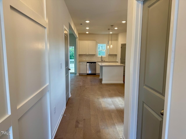 hallway with recessed lighting, a sink, dark wood finished floors, and baseboards