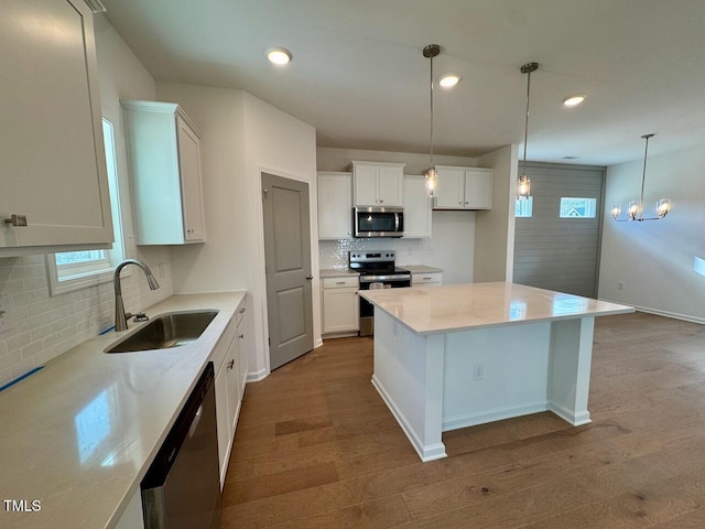 kitchen with appliances with stainless steel finishes, wood finished floors, white cabinetry, a sink, and recessed lighting