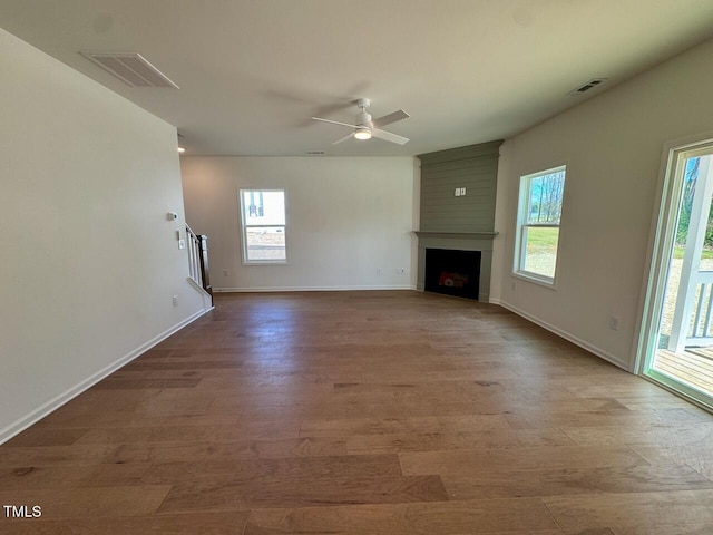 unfurnished living room with a large fireplace, visible vents, and plenty of natural light