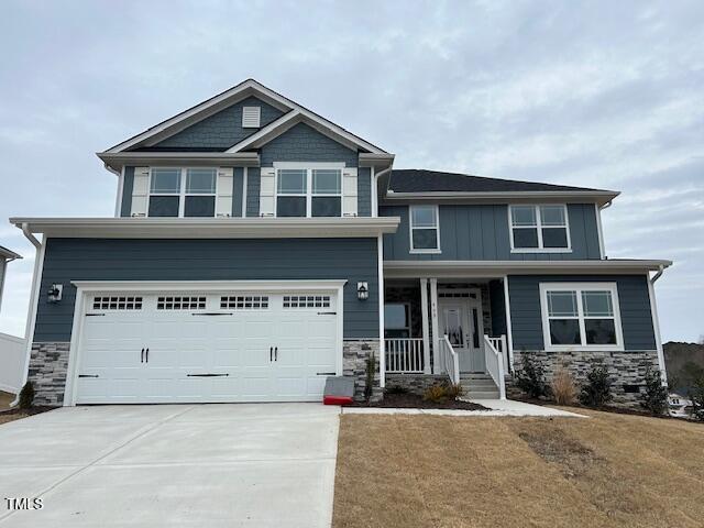 craftsman-style home with a front lawn, a porch, and a garage