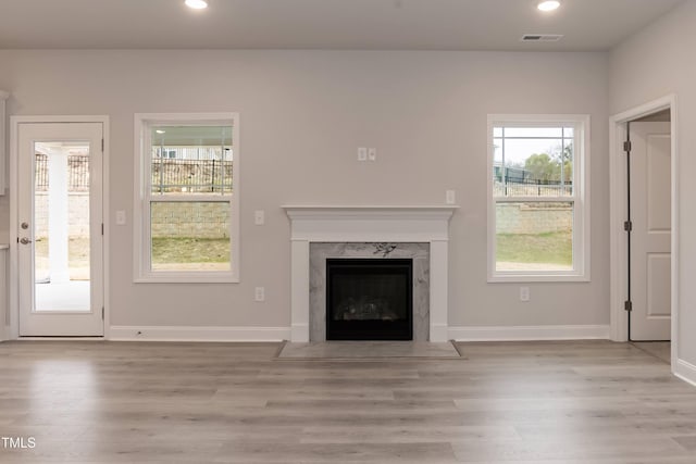 unfurnished living room with a high end fireplace and light hardwood / wood-style flooring