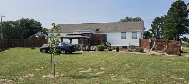 back of property featuring a yard and a gazebo