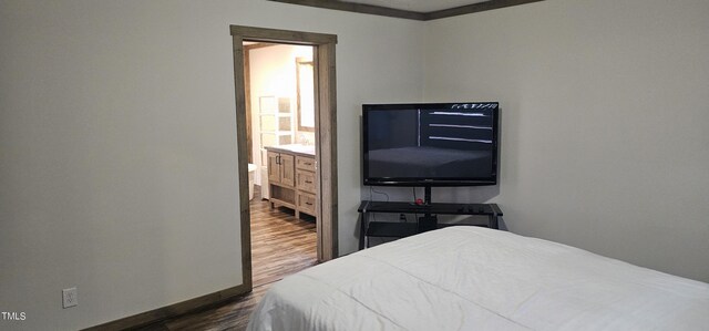 bedroom featuring dark hardwood / wood-style floors, ensuite bathroom, and ornamental molding