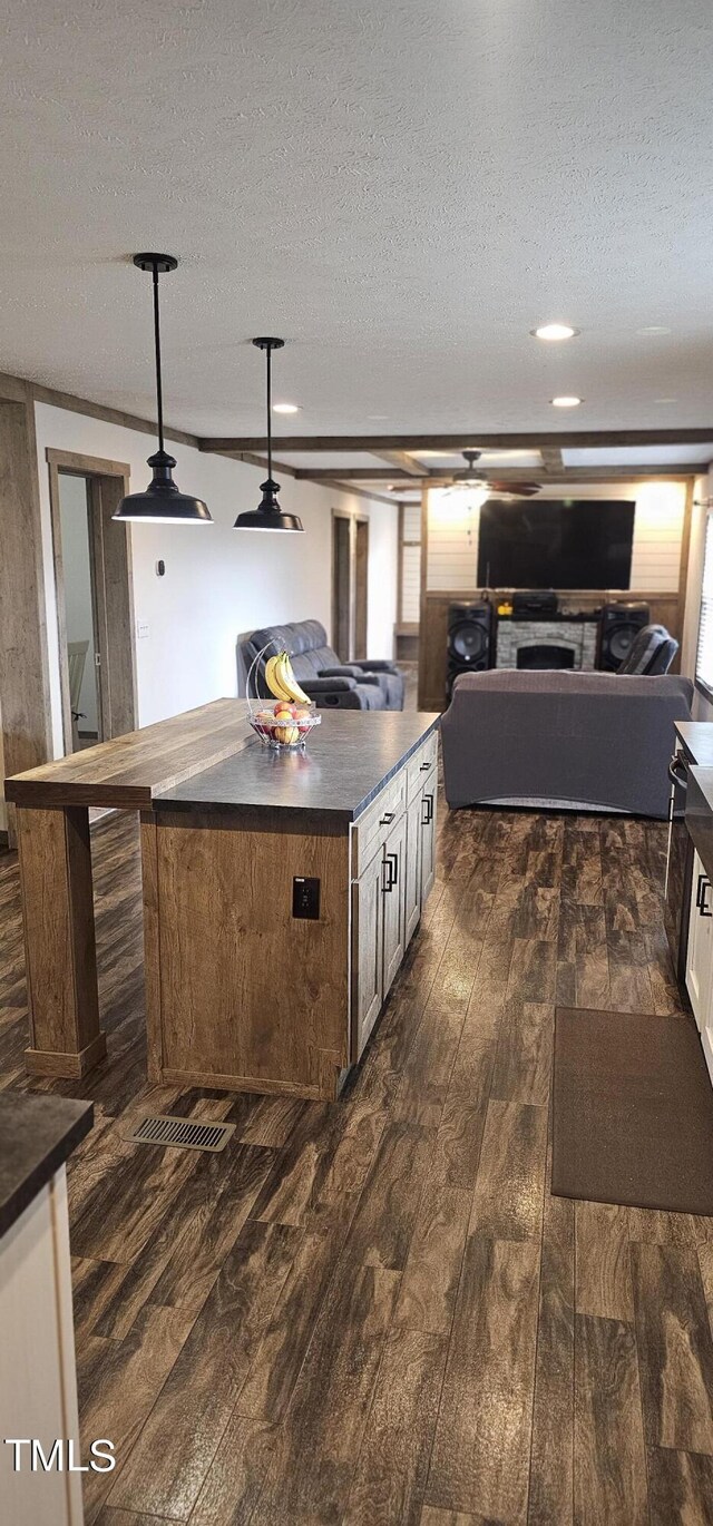 kitchen featuring pendant lighting, a kitchen island, dark hardwood / wood-style floors, and a textured ceiling