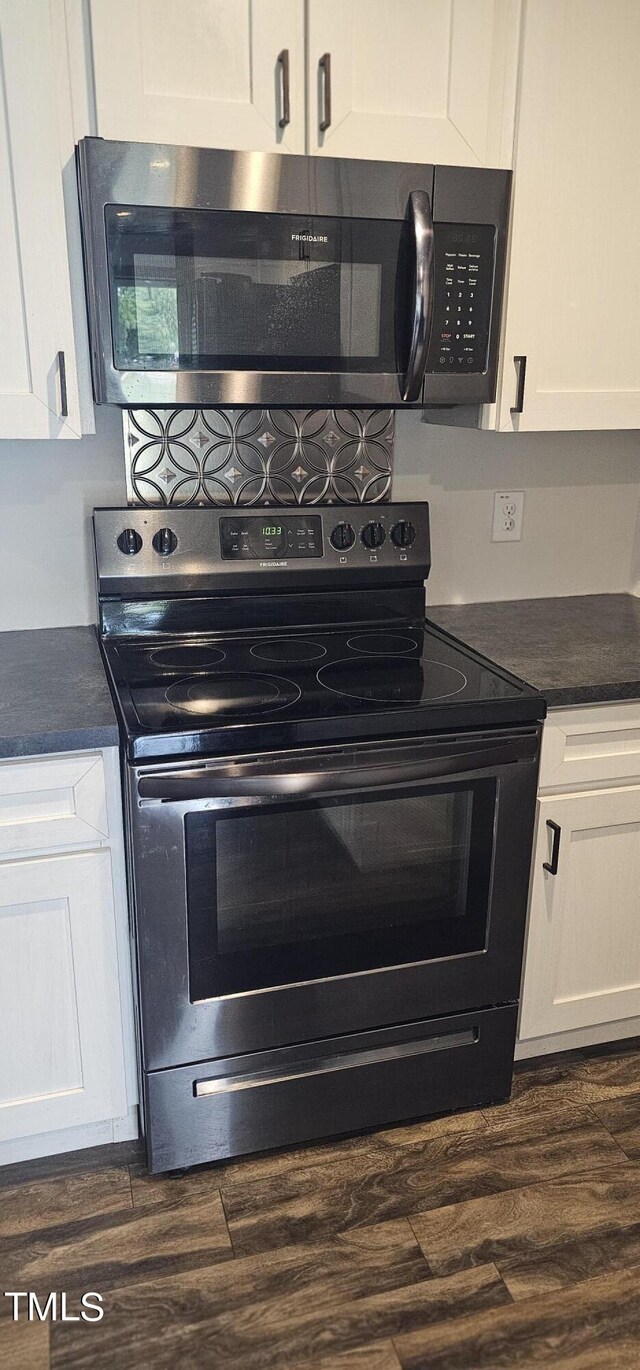 kitchen with dark wood-type flooring, white cabinetry, and stainless steel appliances