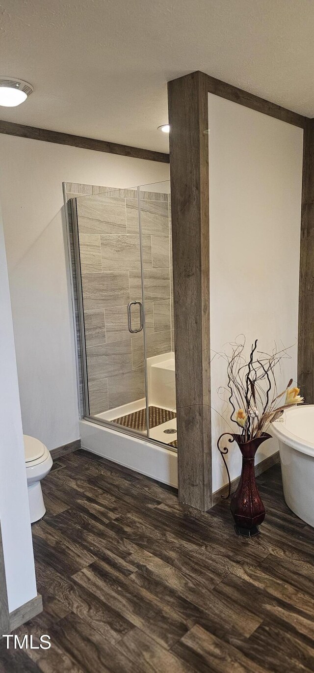 bathroom featuring toilet, plus walk in shower, ornamental molding, a textured ceiling, and hardwood / wood-style flooring