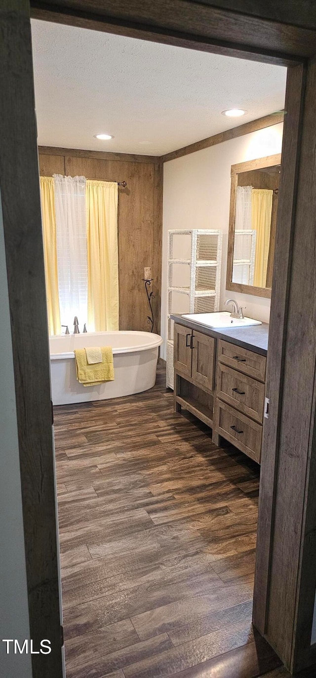 bathroom with vanity, a bath, wood-type flooring, and a textured ceiling