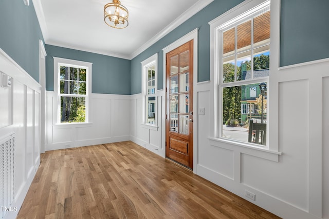 entryway with a notable chandelier, crown molding, a healthy amount of sunlight, and light hardwood / wood-style flooring