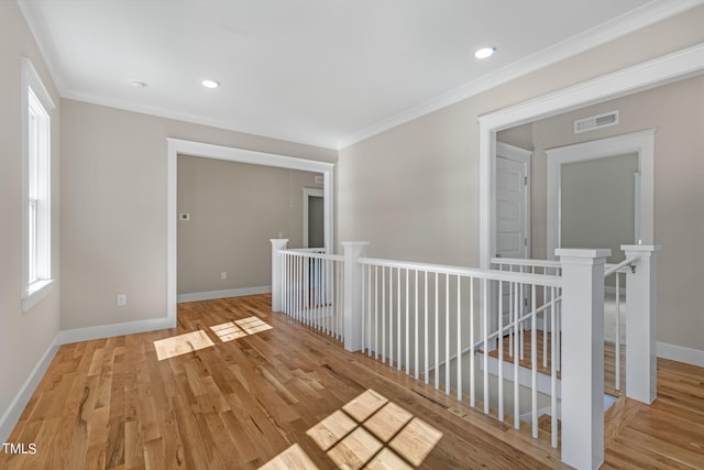 hallway with ornamental molding and light hardwood / wood-style floors