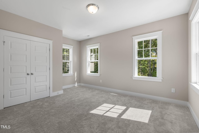 unfurnished bedroom with light carpet and a closet