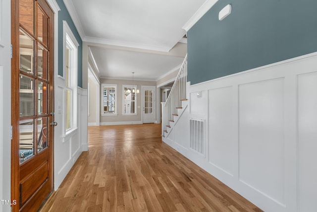 entryway featuring a notable chandelier, ornamental molding, and light hardwood / wood-style flooring