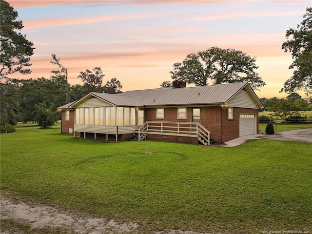 single story home featuring a lawn and a garage