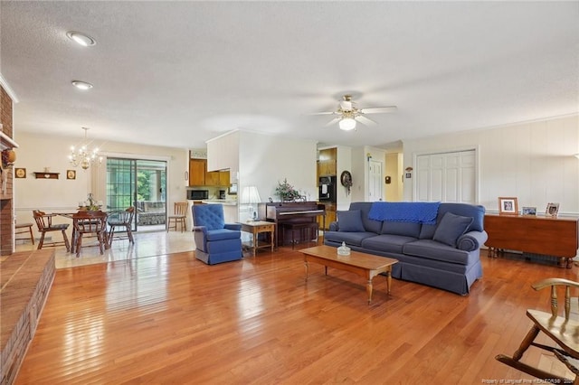 living room with a textured ceiling, light hardwood / wood-style flooring, and ceiling fan with notable chandelier