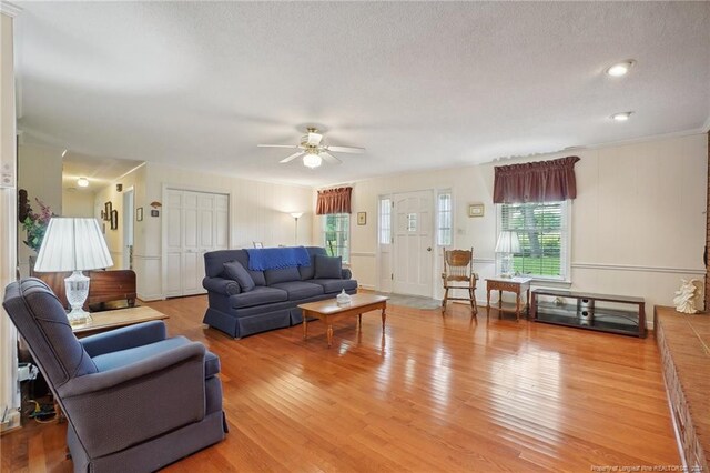 living room featuring ceiling fan, hardwood / wood-style flooring, and a textured ceiling