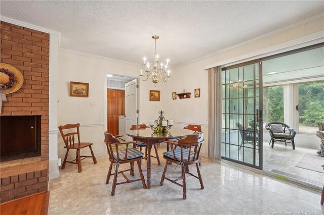 dining room featuring a fireplace, a chandelier, ornamental molding, and a textured ceiling