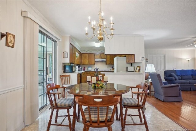 dining room with light wood-type flooring, crown molding, and ceiling fan with notable chandelier