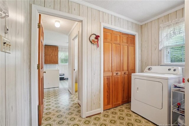 laundry room featuring washer / clothes dryer, plenty of natural light, ornamental molding, and wooden walls