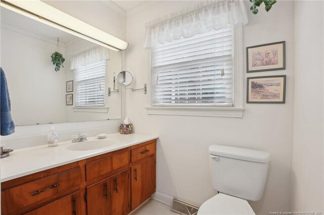 bathroom featuring crown molding, vanity, toilet, and a healthy amount of sunlight