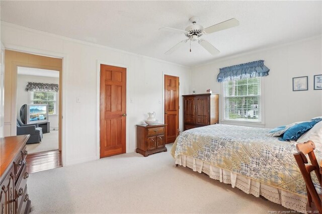 carpeted bedroom with crown molding, multiple windows, and ceiling fan