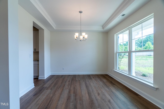 empty room featuring dark wood-type flooring, a wealth of natural light, a raised ceiling, and an inviting chandelier