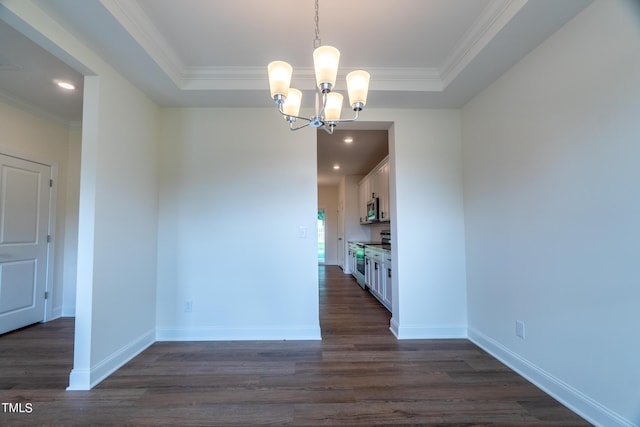 unfurnished dining area with baseboards, ornamental molding, a tray ceiling, dark wood-style floors, and an inviting chandelier