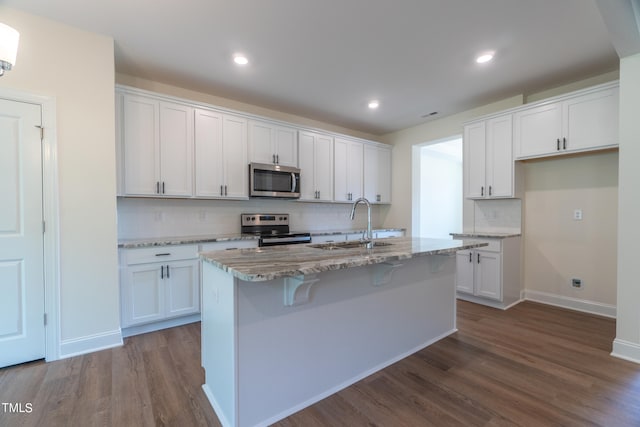 kitchen with an island with sink, stainless steel appliances, sink, and white cabinetry