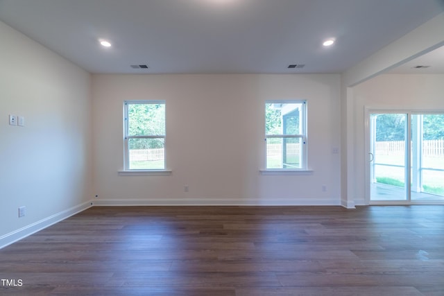spare room with dark wood finished floors, visible vents, and a healthy amount of sunlight