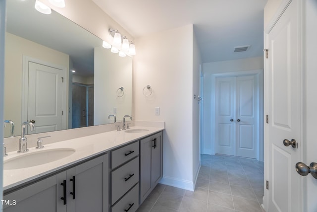 full bath featuring a stall shower, double vanity, a sink, and tile patterned floors