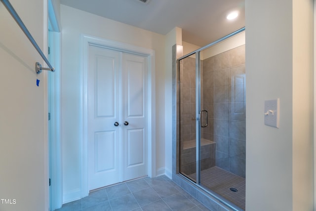 bathroom with a shower with door and tile patterned floors