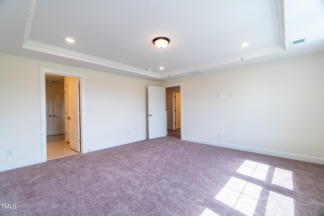 unfurnished bedroom with ensuite bath, a raised ceiling, light carpet, and ornamental molding